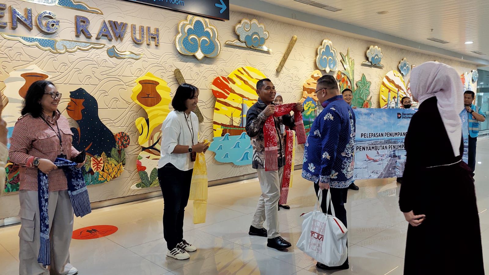 Manajemen Bandara Ahmad Yani mengalungkan kain batik kepada penumpang perdana 2026 (foto: Angkasa Pura)